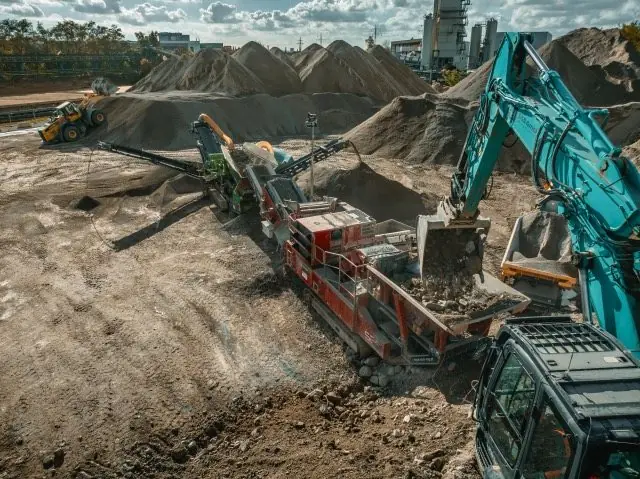 Mobiler Brecher und Bagger zwischen Haufwerken