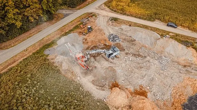 Luftbild eines Aufbereitungsplatzes mit Brecher und Bagger