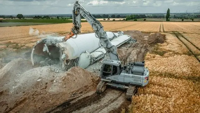 Windkraftanlagen-Rückbau: Bagger zerlegt Turm im Feld